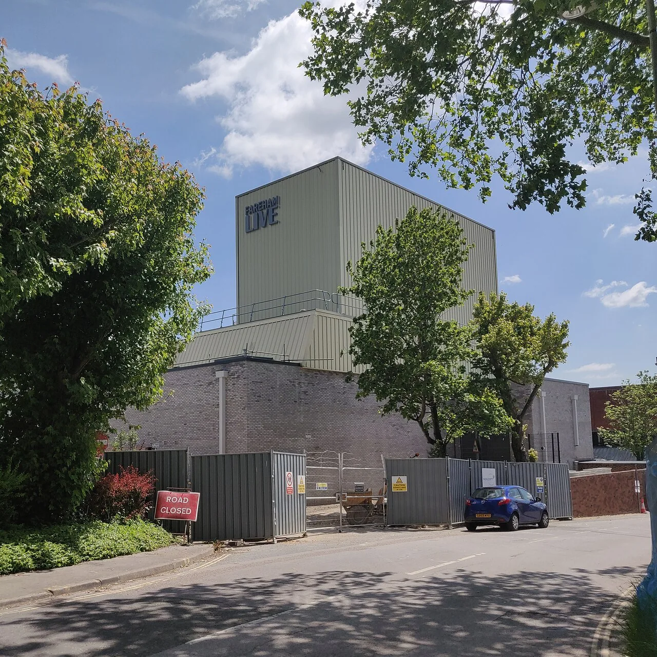The Fareham Live building on Osborn Road, with its name in lettering high on the cladding, seen behind construction hoardings and a road closed sign